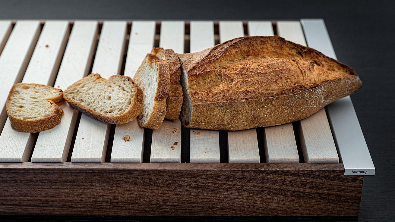 Brot auf dem bulthaup Brotschneidbrett, bei dem auch größere Krümel sicher hindurchfallen und aufgefangen werden.
