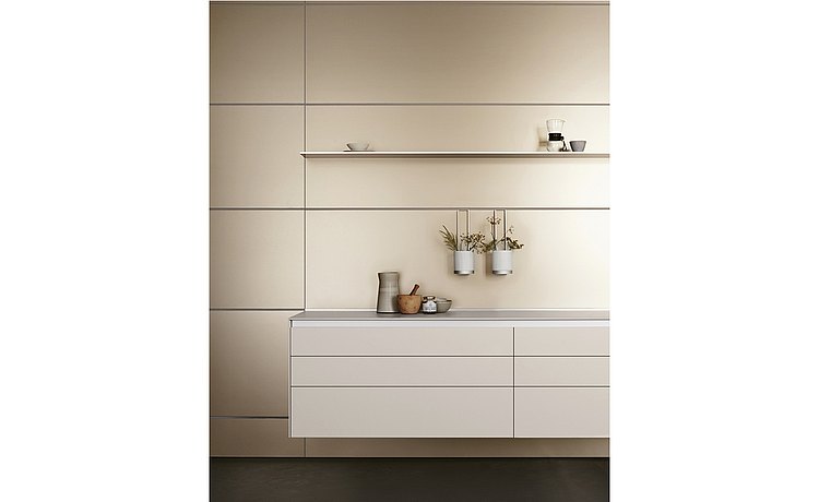 Functional anodized aluminum rear wall with floating kitchen unit, matt-white front panels, and stainless steel surfaces