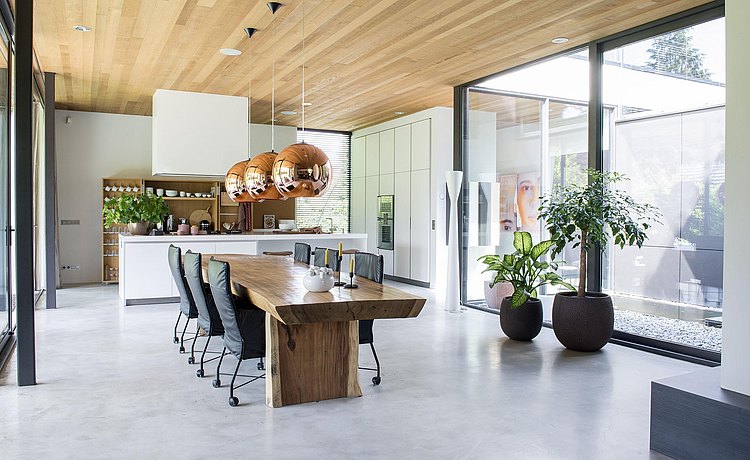 huiskamer met grote houten tafel en doorkijk naar de keuken