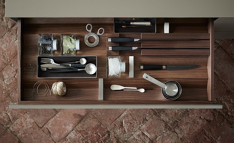 Well organized drawer with dark wood prisms and equipment elements: stainless steel containers, knife block, and stainless steel dividers
