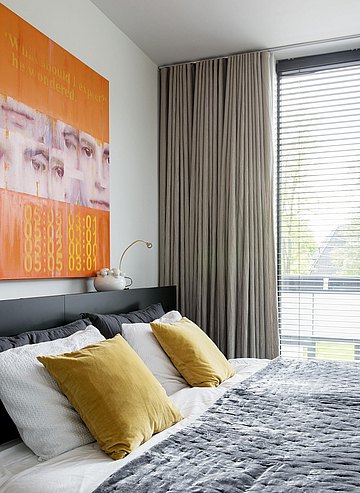 slaapkamer met kunst aan de muur en gekleurde kussens