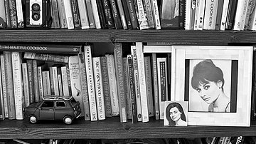 Bücherregal, bestückt mit vielen Kochbüchern und zwei kleinen Portraits von Dalia Penn-Lerner