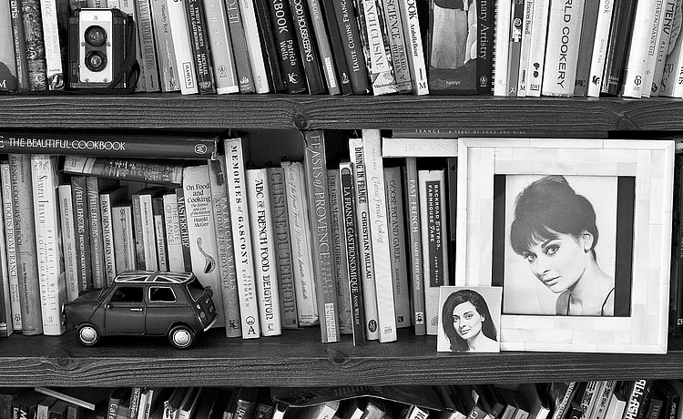 Bücherregal, bestückt mit vielen Kochbüchern und zwei kleinen Portraits von Dalia Penn-Lerner