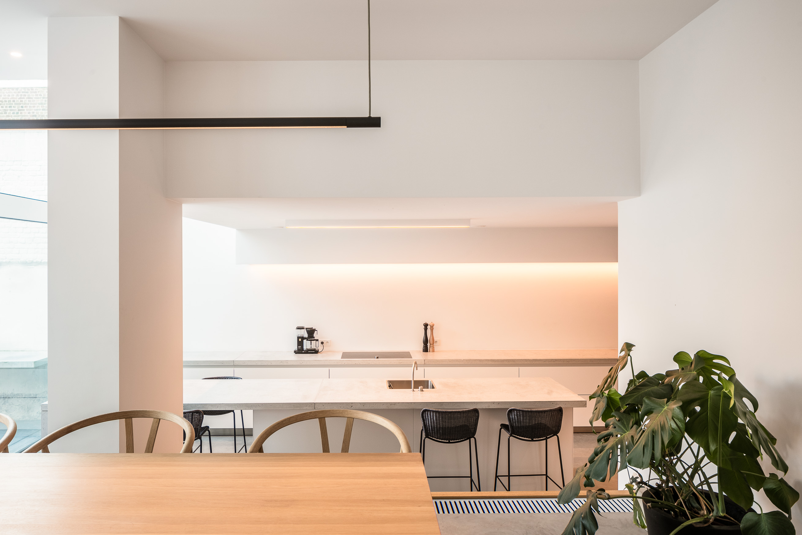 Zicht op de witte keuken met lichtgrijze betonnen werkbladen.